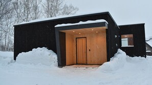 A modern black building with a wooden door and a small porch area. - Luxury 5 Star 3 Bedroom Chalet, Niseko Chalet 1005 (Niseko)