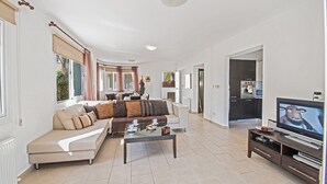 A spacious living room with a sofa, coffee table, and a TV. - Beautiful 5 Star Holiday Villa in a Prime Location in Protaras (Paralimni)