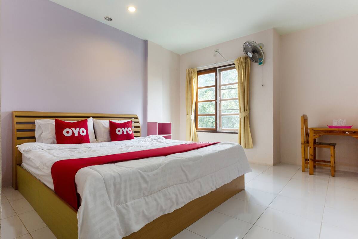 Une chambre à coucher avec un lit, un bureau et une fenêtre avec des rideaux.