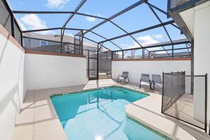 Ein Poolbereich mit Glasveranda, Liegestühlen und Blick auf die umliegenden Gebäude.