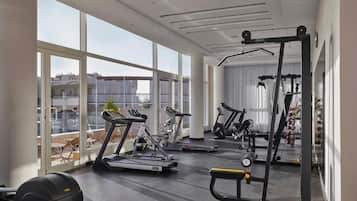Une salle de sport moderne équipée de machines de cardio, de poids libres et d’un miroir.
