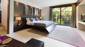 A modern hotel room with a large bed, a desk, and a view of greenery through the window.