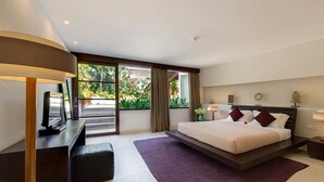 Una habitación de hotel moderna con una cama grande, un escritorio con lámpara y vistas a zonas verdes.