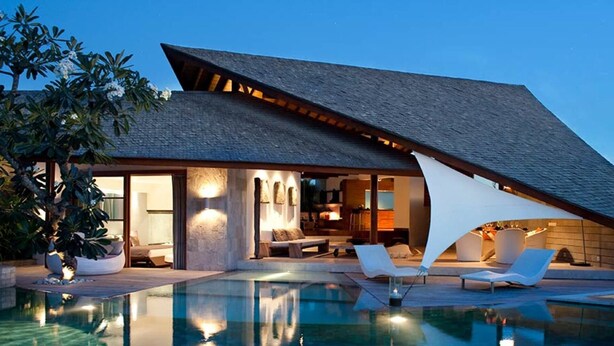 Une villa moderne dotée d’une piscine, d’un espace salon extérieur et d’un coin repas.