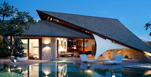 En modern villa med pool, utomhusmöbler och en matplats.