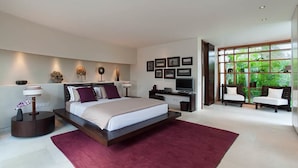 Une chambre moderne avec un grand lit, un bureau, une télévision et un coin salon offrant une vue sur la verdure.