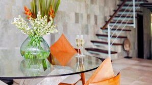 Ein Glastisch mit einer Blumenvase und zwei Sektgläsern.