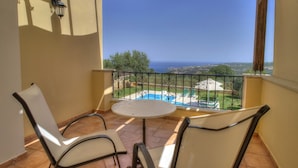 Un balcon avec vue sur la mer, une piscine et un jardin.