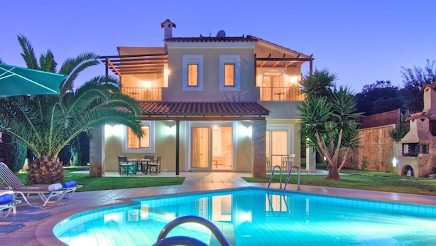 Une maison à deux étages dotée d’une piscine, de mobilier d’extérieur et d’un jardin bien entretenu.
