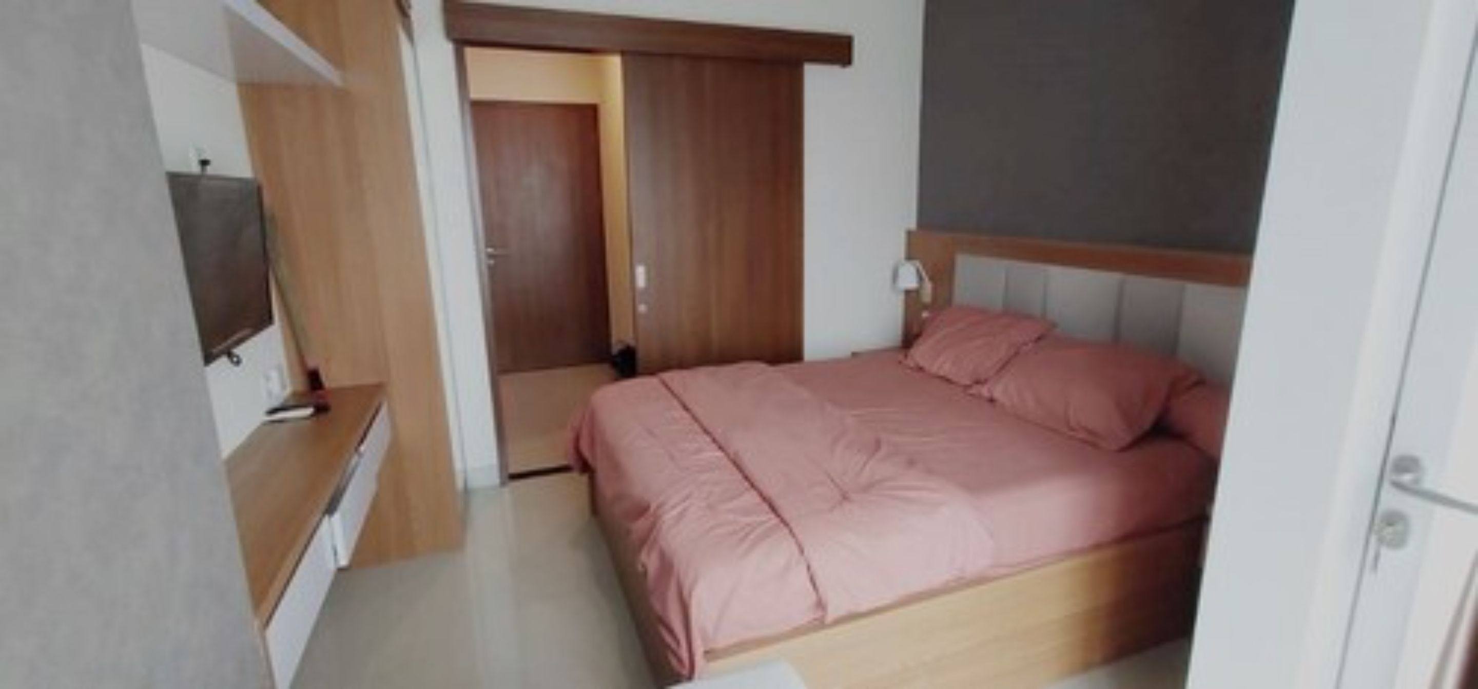 A bedroom with a bed, a TV, and a wardrobe.