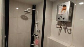 Un baño con ducha, toallero y calentador de agua instalado en la pared.