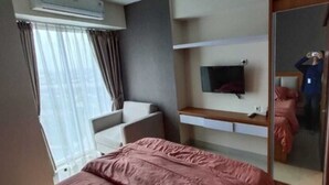 Un dormitorio con cama, una silla, televisor y armario.