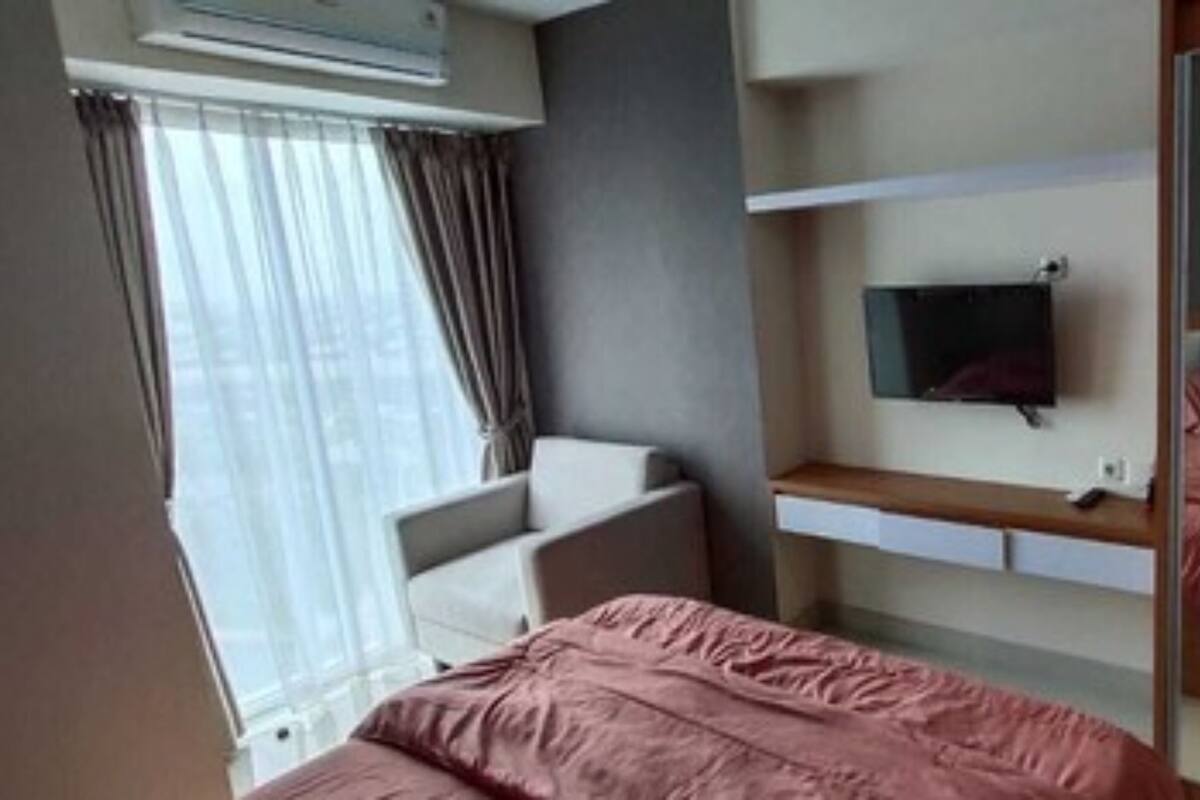 A bedroom with a bed, a chair, a TV, and a wardrobe.