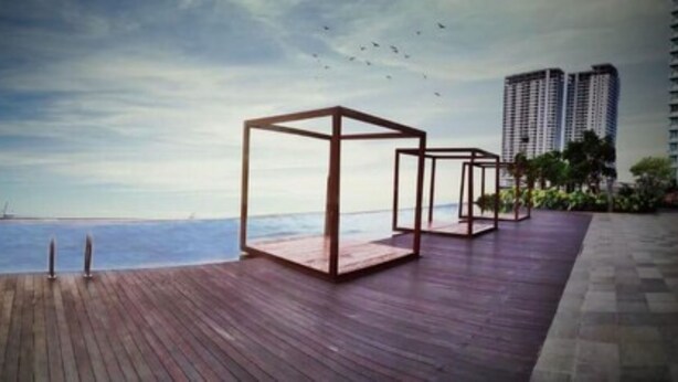 Una terraza de madera con vistas al mar y edificios altos al fondo.