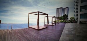 Una terraza de madera con vistas al mar y edificios altos al fondo.