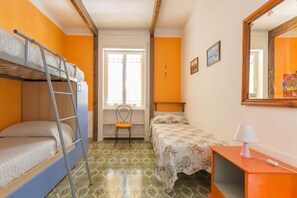 Ein kleiner, farbenfroher Raum mit einem Etagenbett, einem Schreibtisch mit Lampe und einem Stuhl.
