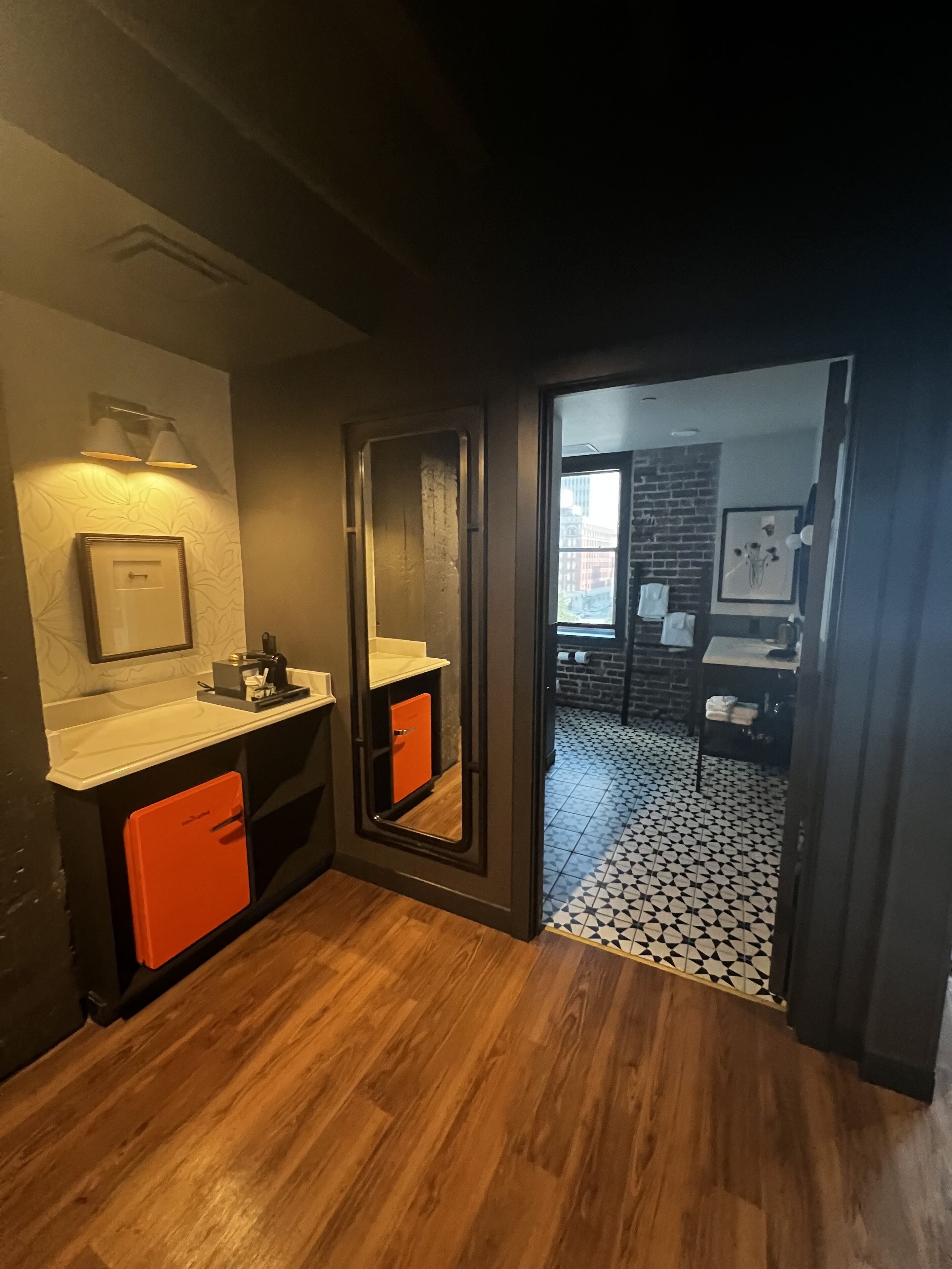 Une salle de bain moderne avec un plancher en bois, un lavabo avec un miroir et un meuble rouge.
