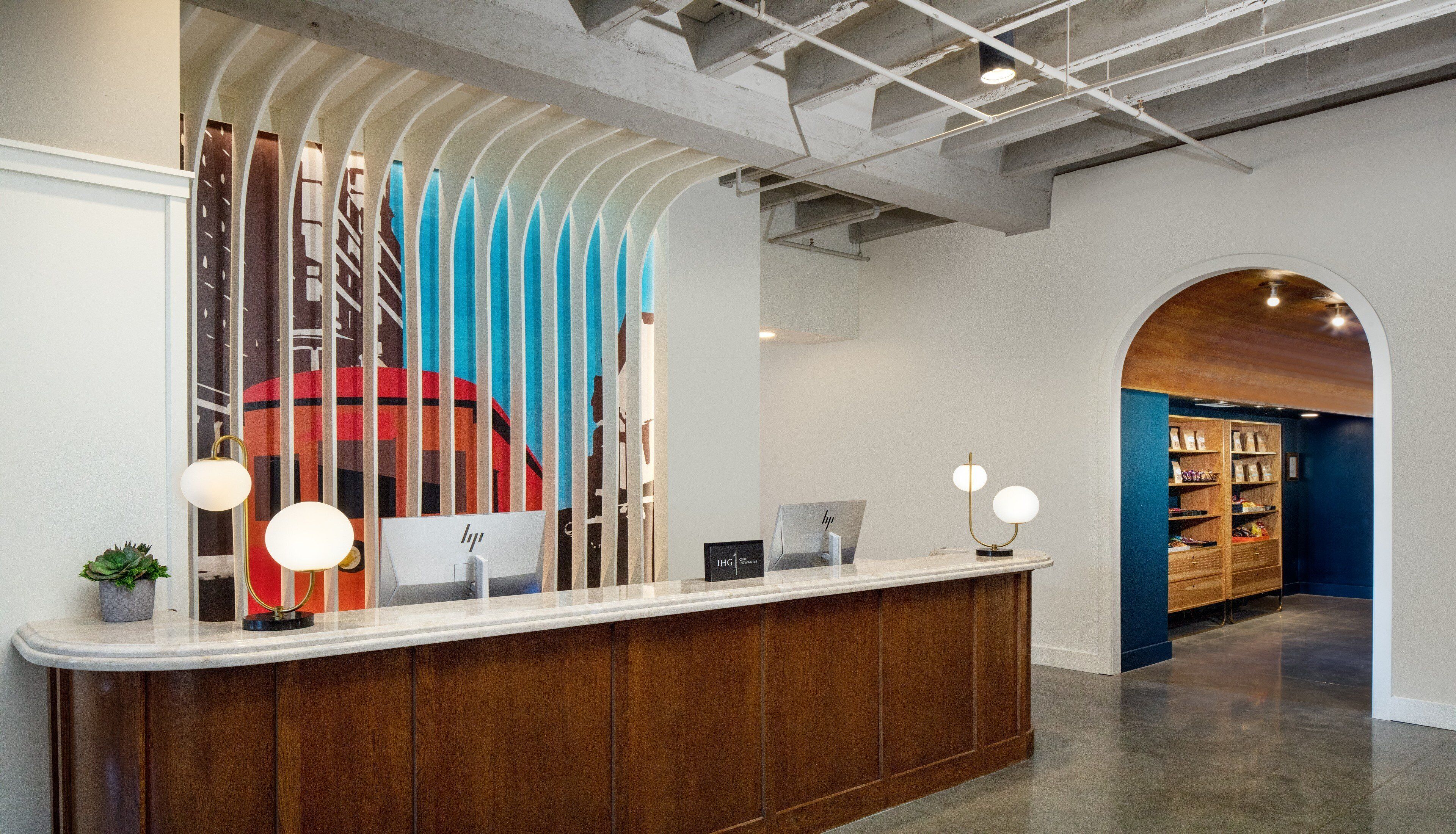 A reception desk with a modern design, featuring a wooden counter and a colorful abstract mural in the background.