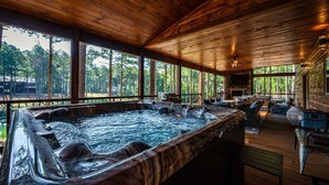 Een houten chalet met een jacuzzi, zitplaatsen buiten en een stenen open haard.