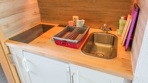 A compact kitchen with a built-in stove, a sink, and white cabinetry. - Ferienwohnung Erika, Deutschland (Blankenburg (Harz))