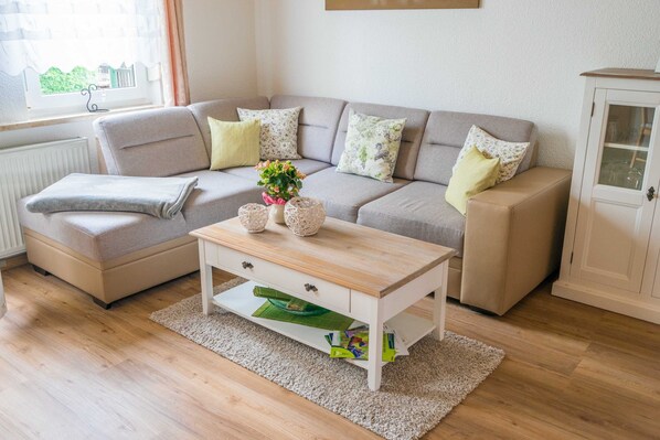 Un salon comprenant un canapé, une table basse, un meuble et une fenêtre donnant sur un paysage agréable.