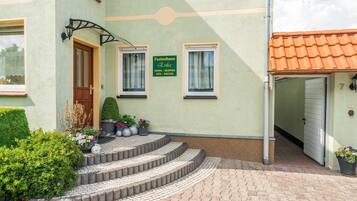 Ein Gebäude mit einem Schild, auf dem 'Ferienhaus Erika' steht, eine Treppe, die zu einer Tür führt, und ein kleiner Gartenbereich mit Blumentöpfen.