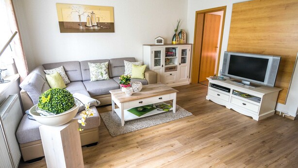 A living room with a sofa, coffee table, TV stand, and a cabinet. - Ferienwohnung Erika, Deutschland (Blankenburg (Harz))