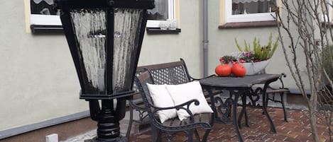 A brick patio with a black lamp post, a bench, and a table with a potted plant.