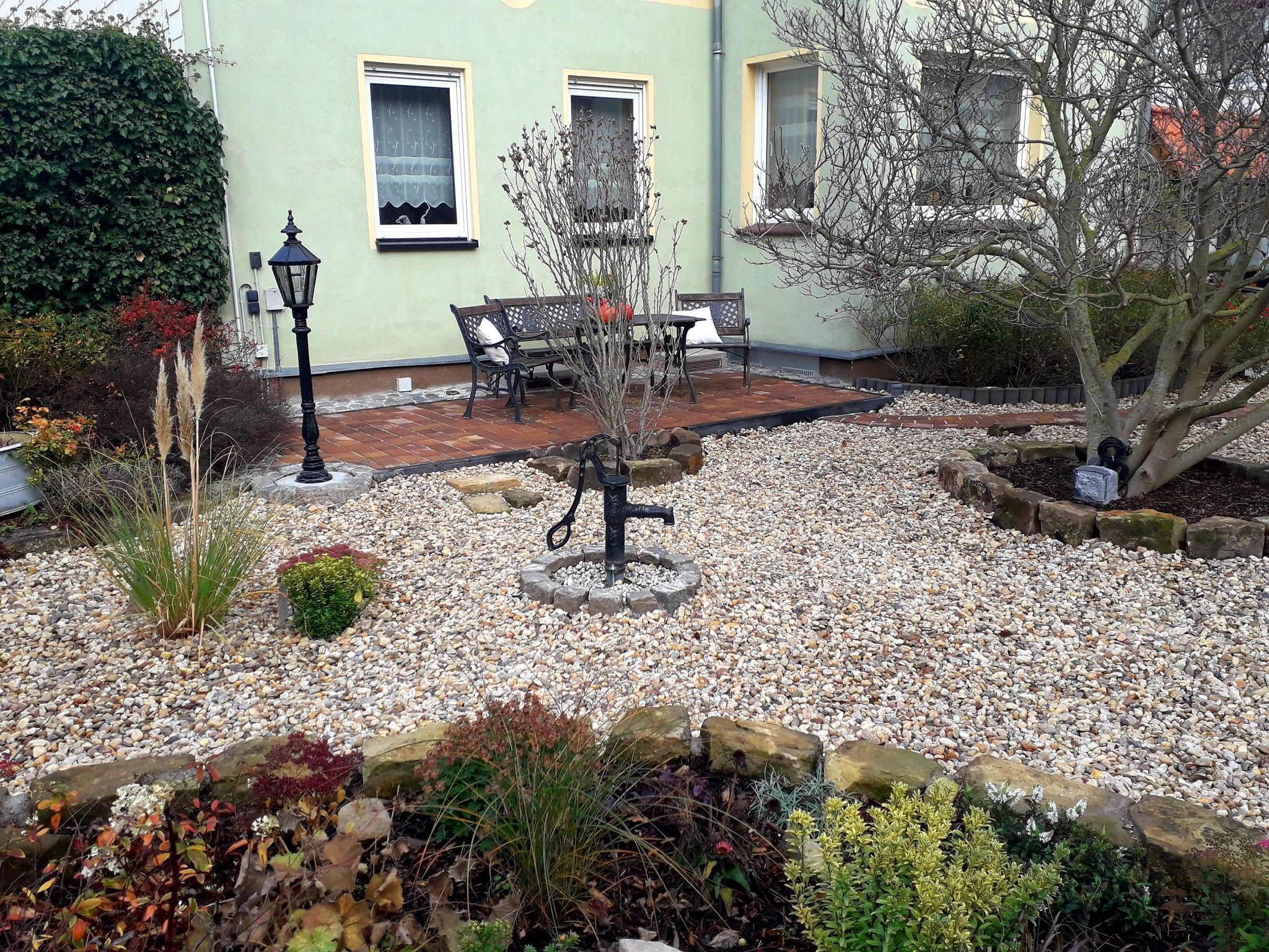 Ein Garten mit Terrasse, Tisch und Stühlen sowie einer Laterne.