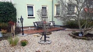 A garden with a patio, a table and chairs, and a lamp post. - Ferienwohnung Erika, Deutschland (Blankenburg (Harz))