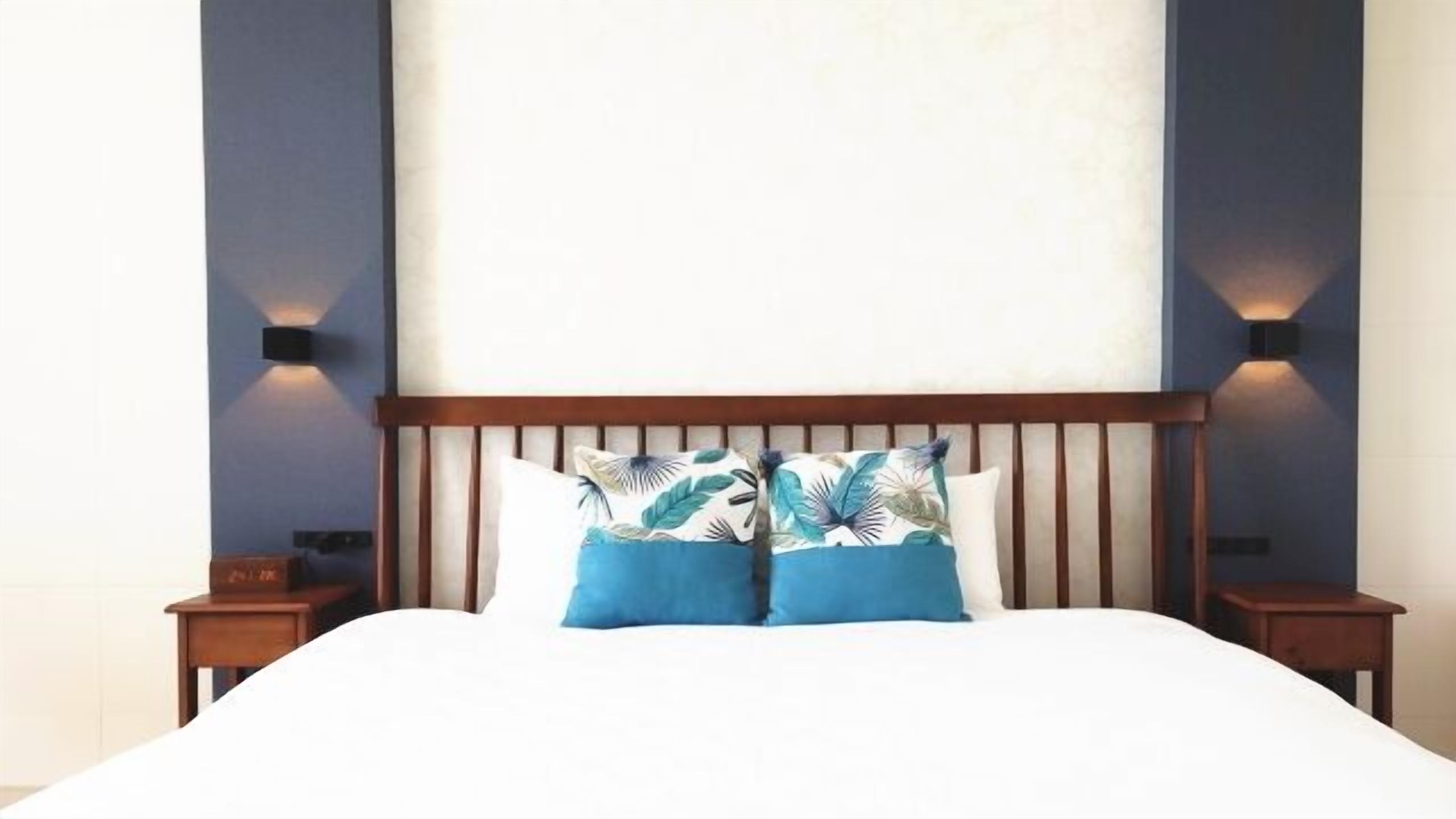 A bed with a wooden headboard, two matching pillows, and two nightstands with lamps.
