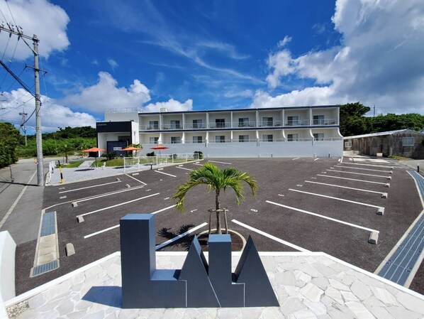 A hotel with a large parking lot, multiple floors, and a modern design.