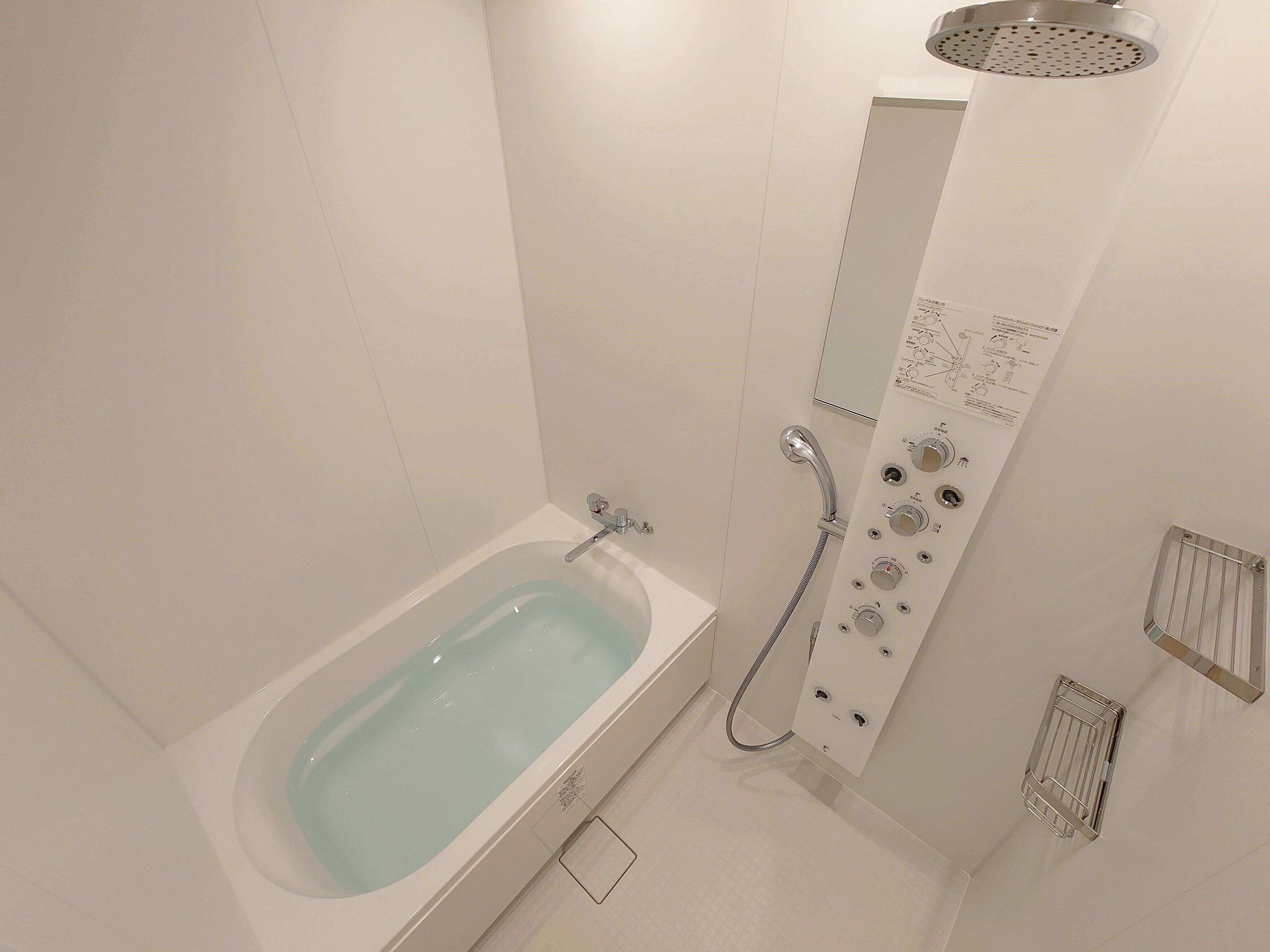 Un baño moderno con bañera, ducha con panel de control y perchero.