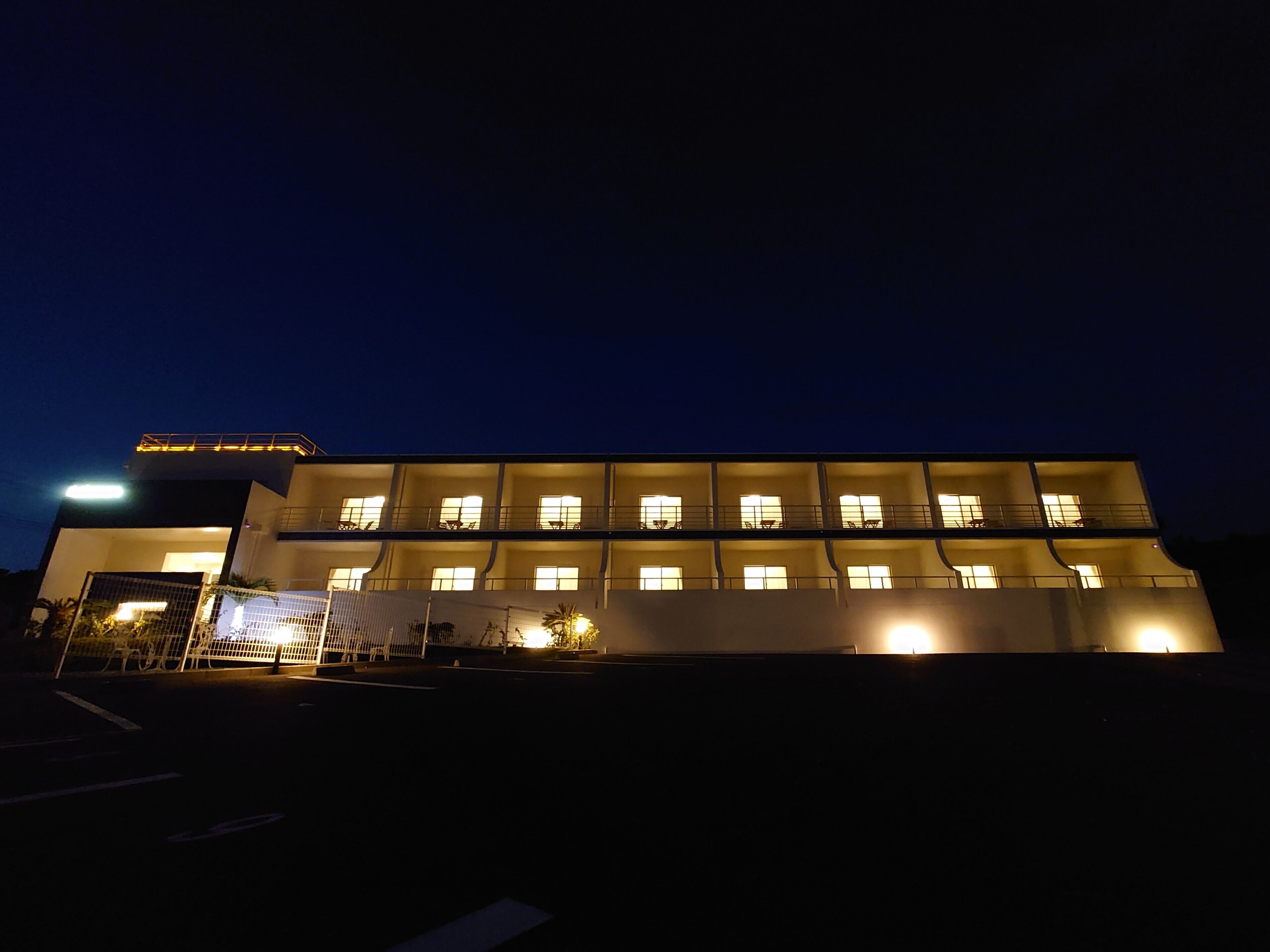 Un edificio a più piani con finestre illuminate e un ingresso chiuso da cancello.