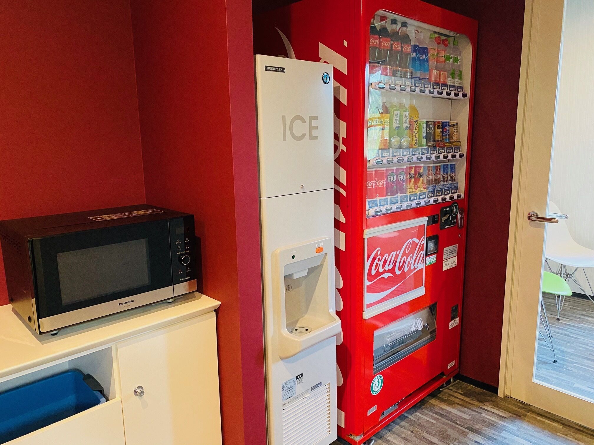 A compact kitchenette with a microwave, ice dispenser, and a Coca-Cola vending machine.