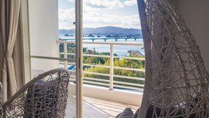 Un balcon avec des fauteuils en osier et une vue sur un pont et la verdure.