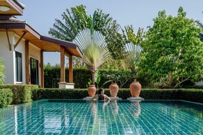 A swimming pool with a tiled surface, surrounded by lush greenery and two large terracotta pots. - Empylean Modern Thai Villa (Rawai)