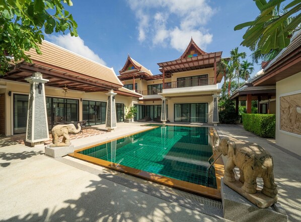 A modern villa with a swimming pool, stone elephant statues, and traditional architectural elements. - Empylean Modern Thai Villa (Rawai)