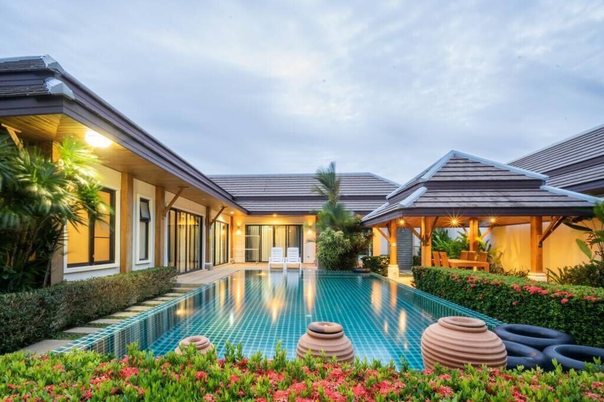 A modern resort with a swimming pool, lounge chairs, and a covered outdoor area.