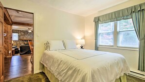 Un dormitorio con una cama grande, una mesita de noche, una lámpara, una ventana con cortinas y vistas al exterior.