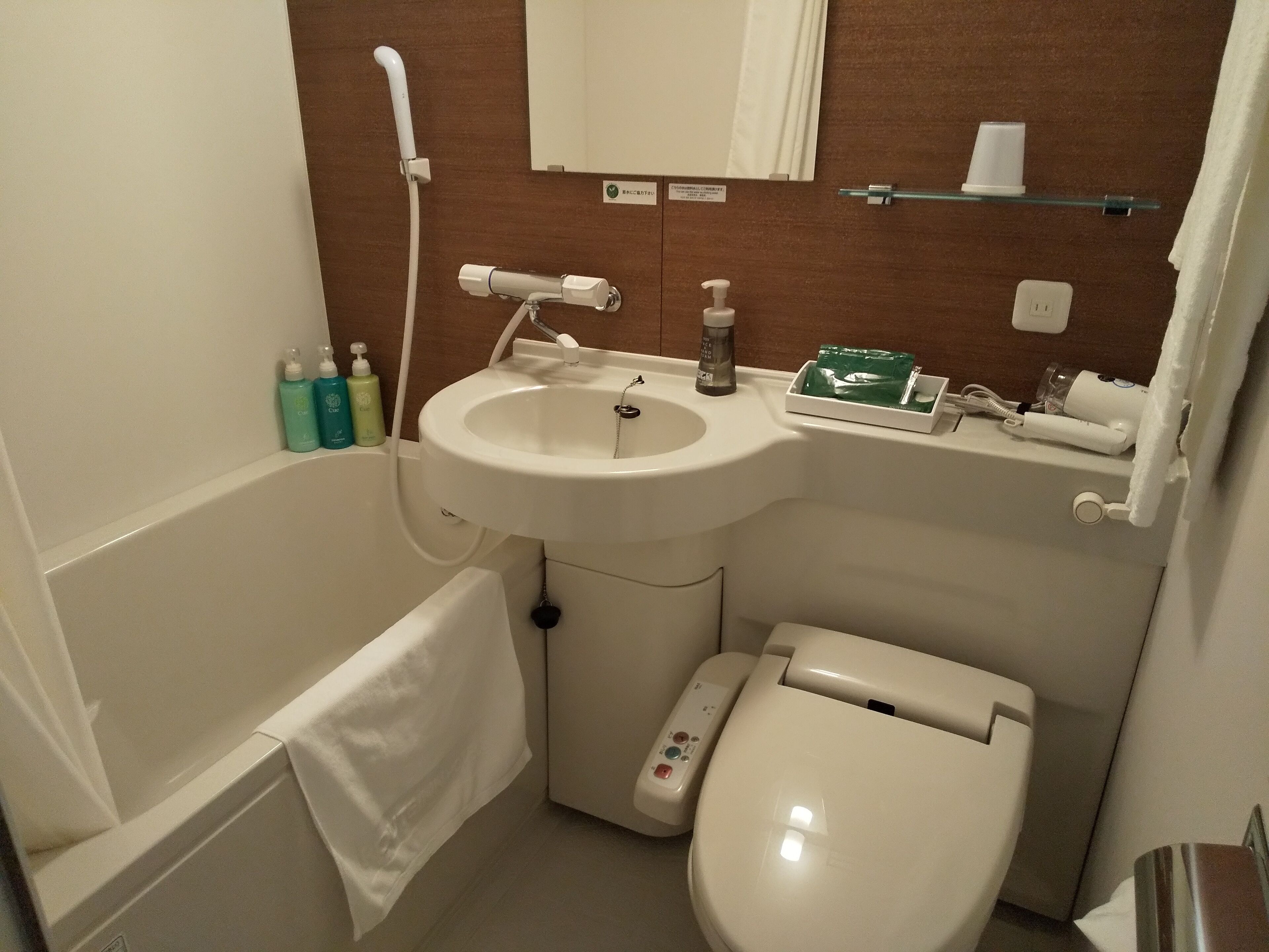 Casa de banho com lavatório, sanita e banheira. Artigos de higiene pessoal no balcão do lavatório.