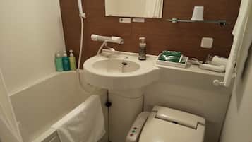 Casa de banho com lavatório, sanita e banheira. Artigos de higiene pessoal no balcão do lavatório.