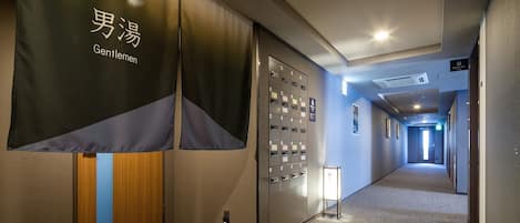 A hotel corridor with a sign reading "Gentlemen" and a row of lockers.