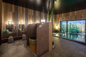Un baño moderno con paneles de madera, encimeras de granito y un amplio ventanal con vistas a un jardín.