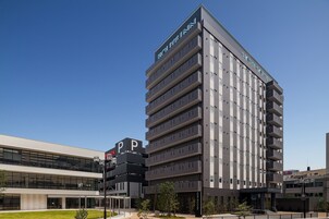 Un hotel de varios pisos con diseño moderno, que cuenta con balcones en cada planta y una señalización destacada.