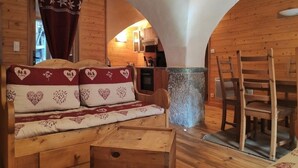 Ein gemütliches Blockhaus-Interieur mit einer Holzbank, einem Esstisch und einem rustikalen Kamin.