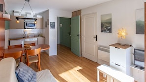 Un espacio habitable compacto con kitchenette, comedor y una zona de estar acogedora.