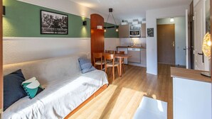 Un espacio habitable compacto con sofá, mesa de comedor y kitchenette.