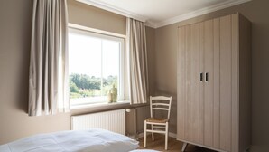 Un dormitorio con dos camas, una ventana con cortinas, un radiador y un armario.
