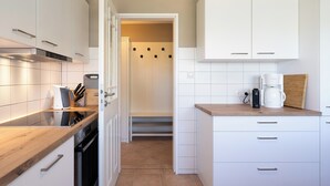 Una cocina moderna con armarios blancos, encimera de madera y horno empotrado.
